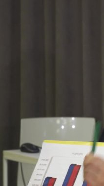 Şık, modern bir ofiste, enerjik genç bir iş kadını deneyimli meslektaşlarını tutkuyla bağlıyor ve ilgi çekici istatistiklerle dolu renkli bir tablo sergiliyor. Bu dinamik sahne, fikirlerin kıvılcım saçtığı yenilik ve takım çalışmasını yayar.