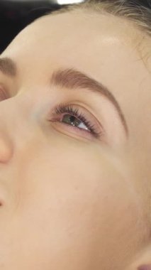 Bu samimi yakın plan çekimde genç, ışıl ışıl bir kadın saç yıkamanın rahatlatıcı deneyiminden zevk alıyor. Yetenekli bir kuaför nazikçe kafa derisine masaj yapıyor. Şelale gibi su ve uzman eller lüks bir rahatlama vahası yaratıyor.