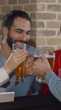 Neşeli arkadaşlardan oluşan canlı bir grup, buzlu bira bardaklarını sıcak ve dostça bir barda tokuşturur. Kırsal tuğla duvarlar ve yumuşak ışıklandırma dostluğu kutlamak ve tadını çıkarmak için mükemmel bir ortam yaratıyor.