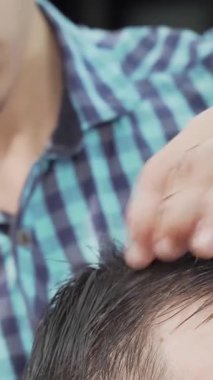 Şık bir berber dükkanında, kendini işine adamış bir kuaför erkek müşterisinin ıslak saçlarını titizlikle tarar, sanatını ve hassasiyetini gösterir. Parlak atmosfer profesyonelliği yansıtıyor. Berber ve beyefendi arasındaki yakın ilişkiyi vurguluyor.