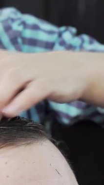 Kendini işine adamış bir kuaför şık bir berber dükkanında sanatını ve hassasiyetini sergileyen bir erkek müşterinin ıslak saçlarını ustalıkla tarar. Parlak atmosfer profesyonelliği yansıtıyor, berberle müvekkil arasındaki samimi bağı vurguluyor.