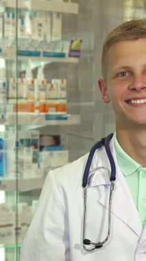 Neşeli bir erkek doktor parlak bir eczanede, elinde bir paketle sizi sağlık çözümlerini araştırmaya davet ederken ışıldıyor. Mesleki kıyafetleri ve düzenli hazırlanmış ilaç ürünlerinin canlı arkaplanı misafirperver bir karşılama yaratıyor.