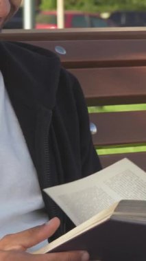 Koyu renk saçlı ve sakallı genç bir adam, kırsal bir parkta oturan kitabının sayfalarını hevesle çevirirken neşe saçıyor. Çevresi canlı yeşilliklerle ve doğanın yatıştırıcı sesleriyle dolu sakin bir sabahtan zevk alıyor.