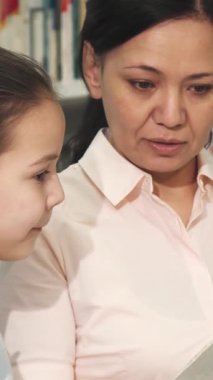 Mutlu bir Asyalı anne ve büyüleyici genç kızı sıcak bir kütüphanede kitap dünyasına dalmış kahkahalar ve meraklarını paylaşıyorlar. Neşeli etkileşimleri sıcaklığı ve sevgiyi yayar, güzel bir şekilde büyütmenin özünü yakalar.