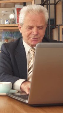 Şık bir kafede, iki iş ortağı güven ve işbirliğini somutlaştıran bir tokalaşma içine girer. Genç adam, şık sakallı, yaşlı meslektaşının yanında oturuyor, o da elinde bir kalemle onların dinamiklerini vurguluyor.