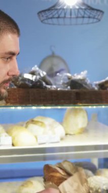 Sıcak bir fırında, olgun bir Asyalı kadın fırıncının yakışıklı erkek müşterisine sıcak bir somun zanaatkar ekmeği uzatması ve hoş bir bağlantı anı yaratması gibi büyüleyici bir sahne gözler önüne seriliyor. Davetkar atmosfer, bir dizi taze pişmiş