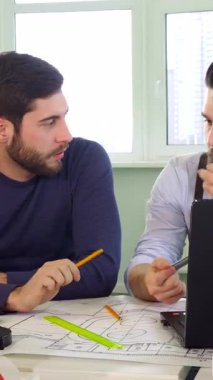 Yaratıcılıkla dolup taşan güneşli bir ofiste, odaklanmış iki erkek mimar canlı bir tartışmaya girişiyor, planlar ve parlak bir dizüstü bilgisayar üzerinde hareketler yapıyorlar. Esmer, sakallı mimar, önemli proje detaylarını özenle vurguluyor.