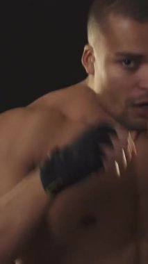 Vahşi bir Afrikalı genç erkek dövüşçü, yakın plan, tutkulu bir gölge boksu içinde, güç yayarak ve kararlılıkla yakalanıyor. Keskin fiziği ve yoğun bakışları, dövüş sanatlarının doğasında olan bağlılığı ve disiplini vurguluyor.