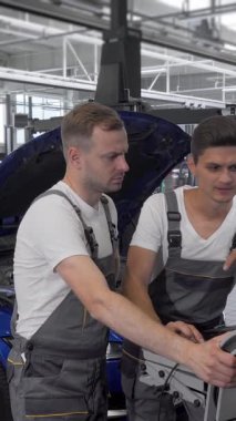 Kendini işine adamış bir tamirci ve özenli asistanı, yoğun bir araba tamir istasyonunun atmosferindeki kritik teşhis sonuçlarını analiz eden bir dizüstü bilgisayarla derinden meşguller. İşbirlikleri uzmanlık ve hassasiyet gösteriyor, her aracı garantiliyor.