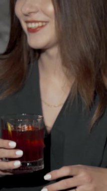 Dinamik bir yakın plan, canlı bir bar ortamında renkli bardaklarını şakırdatan üç şık kadını yakalıyor. Hava kahkaha ve heyecanla dolu, dostluğu kutluyorlar ve unutulmaz anılar yaratıyorlar.