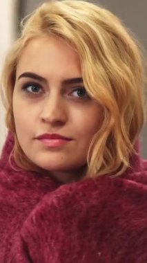 Uzun, kıvırcık sarı saçlı neşeli genç bir kadın şatafatlı pembe bir battaniyenin içine kıvrılıp kıvrılır, ışıl ışıl mavi gözleri neşeyle parlar. Zarif dekorlar ve yumuşak ortam ışıklarıyla süslenmiş şık oda davetkar bir atmosfer yaratıyor.