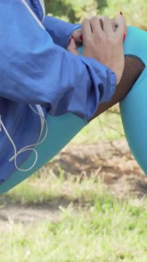 Odaklanmış bir atletik kadın, yüksek ağaçlar ve yumuşak, noktalı güneş ışığıyla çevrili, canlı yeşil bir parkta kollarını uzatıyor. Bu canlandırıcı sahne onun zindeliğe bağlılığını, sağlığın özünü yansıtıyor.