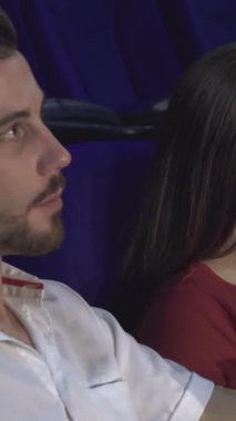 Canlı bir sinemada, iki çift büyüleyici sinema dünyasına dalmış bir şekilde yakın otururlar. Kırmızı gömlekli kız sevinçle ışıldarken ekranın sıcacık parıltısı onların gülüşünü ve patlamış mısırın üzerindeki keyifli anlarını yansıtıyor.