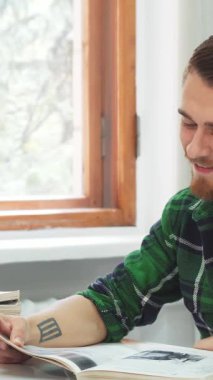 Koyu renk saçlı ve şık sakallı neşeli bir genç adam renkli kitaplarla dolu rahat bir sınıfta oturan kitabındaki komik bir pasaja yürekten gülüyor. Güneş ışığı pencereden içeri doluyor, yüzüne sıcak bir parıltı saçıyor ve