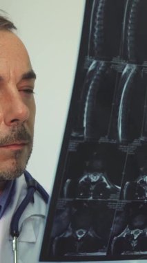 Kendini adamış genç bir erkek terapist kendinden emin bir gülümsemeyle, profesyonellik ve özenle bir röntgeni inceliyor. Parlak ofisi, hasta bakımında güven ve uzmanlık duygusunu arttıran hoş bir atmosfer yayıyor.