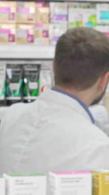 Gıcır gıcır laboratuar önlüğü giymiş arkadaş canlısı bir erkek eczacı renkli ürünlerle dolu canlı eczane raflarıyla çevrili güzel bayan müşterisiyle canlı bir tartışmaya girişir. Etkileşimleri sıcaklığı ve profesyonelliği yansıtıyor.