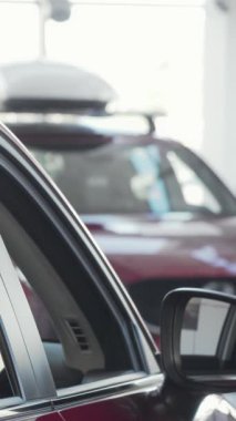 Çekici ve bakımlı sakallı genç bir adam kameraya bakıyor. Parlak bir galeride lüks ve modern bir arabaya yaslanıyor. Neşeli ifadesi, yeni bir araç seçmenin heyecanını yansıtıyor.