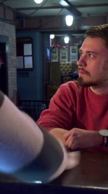 Bir barmen, parlak tezgahı ustalıkla siler ve parlaklığını arttırır. Bu arada, hoş kırmızı kazaklı düşünceli genç beyaz bir adam, bir spor oyununun heyecan verici atmosferine dalmış, birasının tadını çıkarıyor.