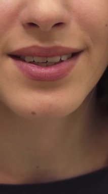 Büyüleyici genç bir kadın bir hava öpücüğü üflüyor, dudakları neşe saçan bir flört jesti ile hafifçe yarılıyor. Yakın plan, parıldayan tenini, mükemmel manikürlü elini ve büyüleyici bir güzellik atmosferi yaratan sıcak gülümsemesini vurgular.