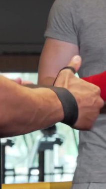 Çekici bir yakın çekim gösterisi iki erkek boksör, biri ustalıkla bileğine kırmızı bir bandaj sararak heyecan verici bir maça hazırlanıyor. Spor salonu somut enerji ve azimle uğulduyor, sporcuları tereddütsüz vurguluyor.