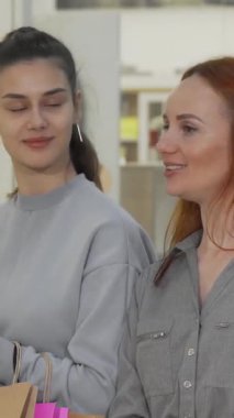 Biri çarpıcı kızıl saçlı, diğeri de modaya uygun gri kıyafetli iki neşeli genç kadın, hareketli alışveriş merkezinde sergilenen şık şeylerden büyüleniyorlar. Bulaşıcı gülüşleri ve kahkahaları, canlı atmosferi aydınlatıyor.