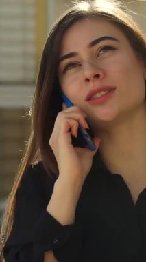 Enfes beyaz bir kadın akıllı telefonuyla sohbet ediyor, canlı bir şehir caddesinde yürürken diğer elinde şık bir kahve fincanı tutuyor. Işıl ışıl gülüşü ve şık siyah elbisesi gençlik enerjisi saçıyor.