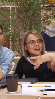 Canlı, genç, beyaz bir adam canlı bir çalışma alanındaki parlak bir dizüstü bilgisayarın etrafındaki kadın meslektaşlarıyla heyecan verici sezgilerini tutkuyla paylaşıyor. Gözlüklü şık esmer kadın hevesle eğilirken, büyüleyici kahverengi saçlı kadın çenesini dinlendiriyor.