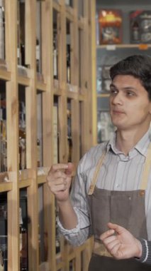 Sakallı bir adam etkileyici bir dizi renkli şarap şişesiyle çevrili büyüleyici bir şarap dükkanında genç bir erkek tezgahtarla hevesle iletişim kuruyor. Davetkar atmosfer sıcaklık ve heyecan saçıyor.