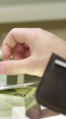 Sofistike bir beyaz müşteri zarif bir şekilde lüks bir butikte şık bir kadın satıcının cüzdanından para veriyor. Satıcı, zarif siyah eldivenler giymiş, göz kamaştırıcı bir mücevher sergiliyor, bu zengin ortamı somutlaştırıyor.