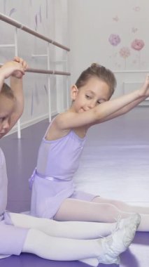 Yumuşak lavanta tayt giymiş iki küçük balerin, canlı mor bir zeminde uyum içinde uzanıyor, narin hareketleri neşe ve adanmışlık saçıyor. Bu büyüleyici sahne çocukluk ruhunu ve sanatı özetliyor.