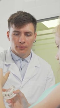 Kendini işine adamış bir erkek dişçi, zarif ve modern bir klinikte dişçi hijyen teknikleri gösteren genç bir kızla tutkuyla etkileşime girer. Bu iç açıcı sahne dikkat ve profesyonelliği yansıtıyor, dişçilerin beslenmeye olan bağlılığını vurguluyor