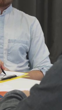 Gıcır gıcır açık mavi gömlekli genç sakallı bir işadamı canlı bir şirket toplantısına katılırken derinden not almakla meşgul. Modern ofis ayarları yaratıcılık ve işbirliği ile uğulduyor, ruhu somutlaştırıyor.