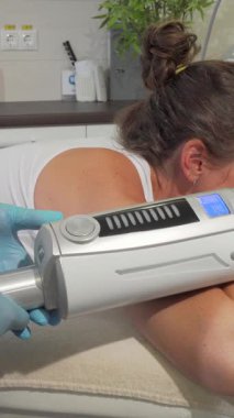 Olgun bir kadın lüks bir tedavi masasına yaslanmış şık bir güzellik salonundaki canlandırıcı sonosferler masaj terapisinin tadını çıkarıyor. Özenli güzellik uzmanı, eldivenli ve odaklı, gelişmiş cihazı ustalıkla manevra yapar, rahatlığı arttırır ve