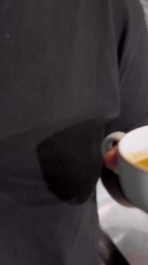 Kendini işine adamış bir barista sıcak sütü sıcak bir kahve bardağına dökerek yüzeyde dans eden karmaşık latte sanatını icra eder. Bu büyüleyici an, kahve işçiliğinin tutkusunu ve hassasiyetini yansıtıyor.