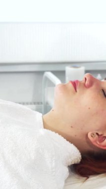 El değmemiş beyaz önlüklü yetenekli bir kozmetikçi kadın ultrasonik bir makine kullanıyor ve dingin genç bir kadının doğal güzelliğini arttırıyor. Işıl ışıl ciltli müşteri, güzellik uzmanının kibarca yaptığı gibi ferahlatıcı bir yüz soyma ameliyatına giriyor.