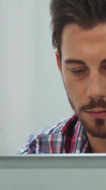 Koyu renk saçlı ve düzgün kesilmiş sakallı kendini adamış genç bir adam, yoğun bir şekilde dizüstü bilgisayarında daktilo ediyor, içi doğal ışık dolu parlak bir sınıfa daldırılmış. Sıcak güneş ışığı pencereden süzülüyor, kareli gömleğinin üzerine bir parıltı saçıyor,