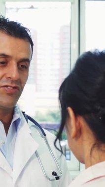 Modern dekor ile süslenmiş güneşli bir ofiste, sıcak kalpli bir doktor genç bir kadınla anlamlı bir konuşma yapar ve ona paha biçilmez sağlık tavsiyeleri sunar. Etkileşimleri, kadının omzunu hafifçe okşayarak vurgulanır.