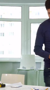 Parlak, modern bir ofiste, kendini adamış genç esmer bir mimar, dikkatle parlak bir masanın üzerine eğilir, dikkatle hazırlanmış planların yanına göz alıcı turuncu bir şapka koyar. Ciddi bir beyaz erkek inşaat mühendisi, kuyusu var.