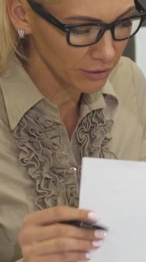 Bu yakın plan çekimde iki iş kadını, profesyonellik ve takım çalışmalarını vurgulayarak önemli belgeler üzerinde hararetli bir tartışmaya daldı. Renkli çizelgeler ve grafiklerle süslenmiş canlı ofis ortamı atmosferi güçlendirir.