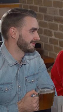 Canlı bir arkadaş grubu, sıcak bir barda bira bardaklarıyla neşeli bir şekilde kadeh kaldırıyor. Kırsal tuğla duvarlara karşı kahkahalar atıyorlar. Işıkların sıcak parıltısı davetkar bir atmosfer yaratır, yoldaşlığın şenlikli ruhunu güçlendirir ve kutlar.