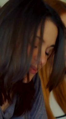 Çekici bir kız öğrenci, neşeli bir şekilde saçlarına dokunuyor. Nişanlı sınıf arkadaşlarıyla dolu bir konferans salonunda kendine güven ve neşe saçıyor. Bu yakın plan, onun ışıl ışıl gülüşünü yakalar. Yumuşak ışık ve canlı bir çevre çerçevesi ile çerçevelenir ve davetkar bir davet yaratır.