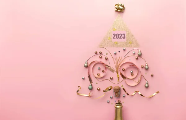2023ゴールド装飾とシャンパンボトルから出てくる泡 クリスマスツリーの形 休日の新年のお祝いのコンセプトを作成します ロイヤリティフリーのストック写真