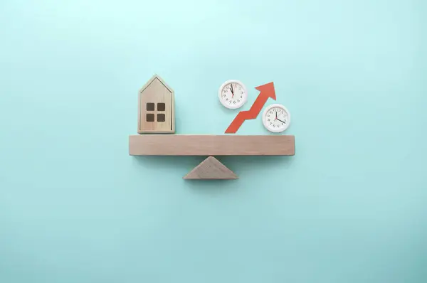 Miniaturhaus Und Prozentzeichen Mit Uhren Die Auf Einer Wippe Balanciert Stockbild