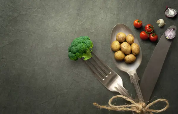 关于餐具 有机食品概念的微型土豆 洋葱和西兰花 免版税图库照片