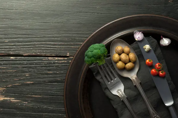 关于餐具 有机食品概念的微型土豆 洋葱和西兰花 图库照片