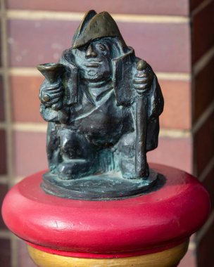 Suffolk, İngiltere - 28 Ekim 2023: Sudbury, Suffolk 'taki Talbot Patikası' ndaki kırmızı bir kazıktaki yolsuzluğu tasvir eden çürük borough heykeli. İzler Sudbury 'nin tarihini gösteriyor..