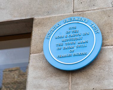 Suffolk, İngiltere - 28 Ekim 2023: Suffolk 'un tarihi Sudbury kasabasında bulunan mavi bir plaket, The Rose and Crown Inn' in eski yerini ve Charles Dickens ile olan bağlantısını gösteriyor..