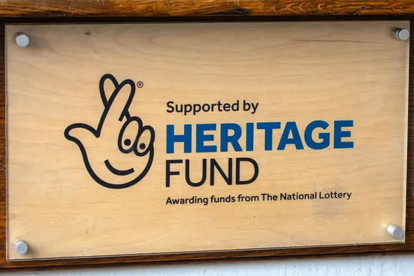 stock image Somerset, UK - September 13th 2023: A National Lottery Heritage Fund plaque on the exterior St. John the Baptist church in Glastonbury, Somerset, UK.