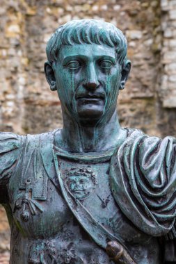 Londra, İngiltere - 3 Nisan 2024: Londra 'da arkasında Londra Duvarı kalıntıları olan Roma İmparatoru Trajan' ın heykeli. Duvarın o bölümü Romalılar tarafından yapıldı..