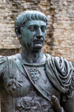 Londra, İngiltere - 3 Nisan 2024: Londra 'da arkasında Londra Duvarı kalıntıları olan Roma İmparatoru Trajan' ın heykeli. Duvarın o bölümü Romalılar tarafından yapıldı..